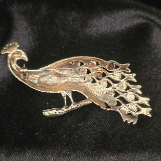 Gold tone enamel peacock brooch with green and purple body and blue stones