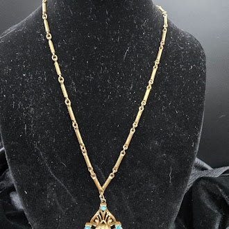 Gold tone filigree pendant necklace with blue crystal and faux pearl frame