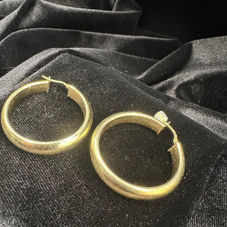 Gold tone hoop earrings with rounded tubular profile
