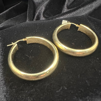 Gold tone hoop earrings with rounded tubular profile
